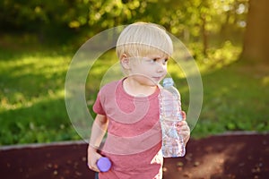 Little boy drinking water during workout with dumbbells
