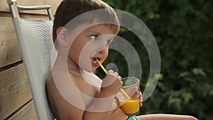 Little boy drinks orange juice through a straw