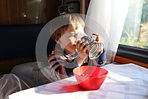 Little boy drinks tea in speeding train