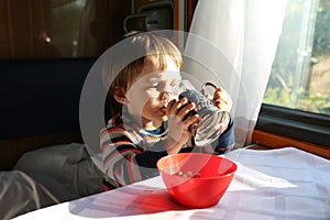 Little boy drinks tea in train