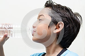 Little boy drinks water from a bottle after excercise