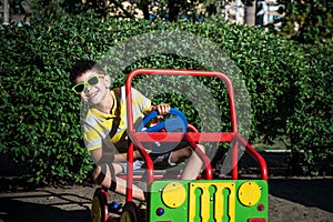 Little boy driving big toy car and having fun, outdoors