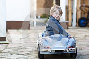 Little boy driving big toy car, outdoors