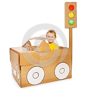 Little boy driving his handmade cardboard car