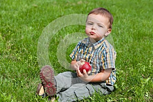 Little boy eating apple outside