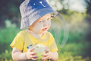 Little boy eating apple in summer