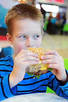 Little boy eating burger