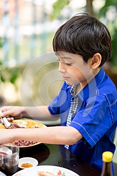 Little boy eating for food meal in the restuarant