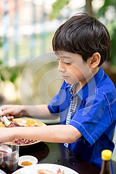 Little boy eating for food meal in the restuarant photo