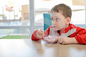 The little boy eating fruit yoghurt in a bowl