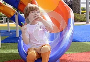 little boy eating green lollipop candy outdoors on playground,. Sweet tooth. .