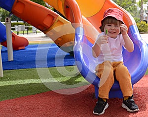 little boy eating green lollipop candy outdoors on playground,. Sweet tooth. .