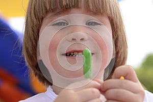 little boy eating green lollipop candy outdoors on playground,. Sweet tooth. .