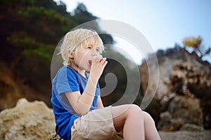 Little boy is eating peach during walking. Nature lover