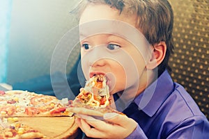Little boy eating pizza at cafe