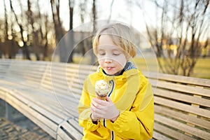 Little boy eating tasty ice cream outdoors during family stroll. Child have a snack on the go. Gelato is loved delicacy of kids.