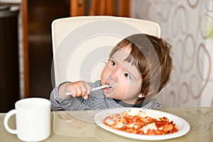 Little boy eats food from a fork in a cafe. A little boy eats food from a fork in a cafe. Family holidays, mom and son relax in a