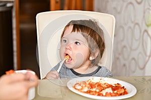 Little boy eats food from a fork in a cafe. A little boy eats food from a fork in a cafe. Family holidays, mom and son relax in a