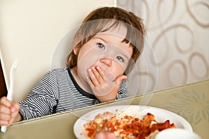 Little boy eats food from a fork in a cafe. A little boy eats food from a fork in a cafe. Family holidays, mom and son relax in a