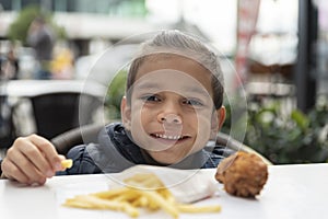 Little boy eats french fries and chicken