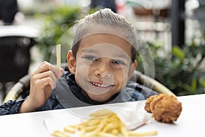 Little boy eats french fries and chicken