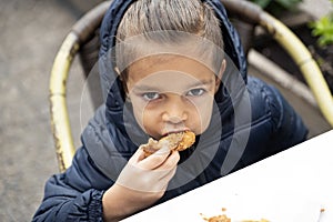 Little boy eats fried chicken.