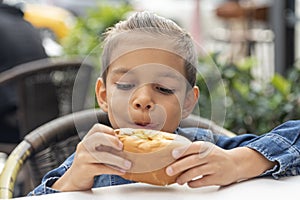 Little boy eats sandwich at fast food restaurant