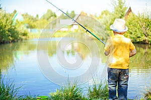 Little boy is engaged in fishing in a pond. Child with a dairy i