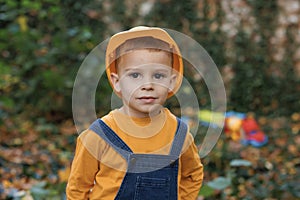 Little boy engineer builder architect with safety helmet, on background construction crane on site. Portrait of kid boy