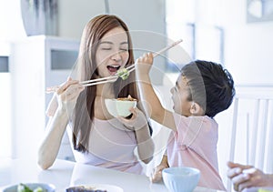 Little boy  enjoy eating food with  mother. Happy Asian  family having dinner at home