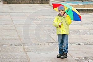 Little boy enjoying rainy weather in city street. Happy kid wuth colorful umbrella outdoors
