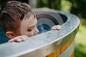 Little boy enjoying summer time in outdoor pool with his family, having fun.