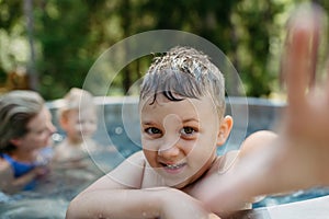 Little boy enjoying summer time in outdoor pool with his family, having fun.