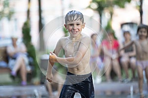 A little boy enjoys the cold waters of a fountain