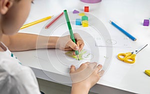 A little boy enthusiastically draws toy money with colored pencils for the game. Selective focus. Family budget