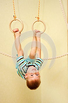 Little boy exercising on gymnastic rings