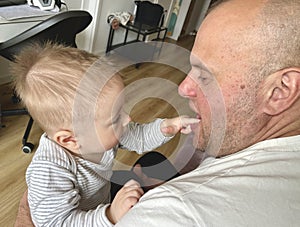 Little boy explores looking at grandfather's mouth