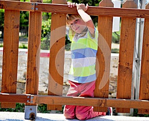 Little boy at the fence of playground