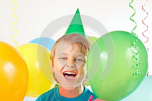 Little boy in festive cap with holiday balls and streamer