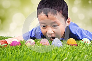 Little boy finding easter eggs on grass