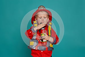 A little boy in a fireman costume plays and dreams of putting out the fire. Fireman on a blue background.