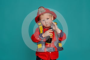 A little boy in a fireman costume plays and dreams of putting out the fire. Fireman on a blue background.