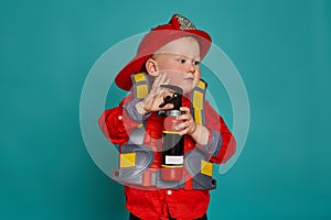 A little boy in a fireman costume plays and dreams of putting out the fire. Fireman on a blue background.