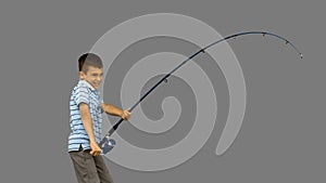 Little boy fishing on grey screen