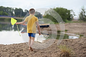 A little boy with a fishing net walks