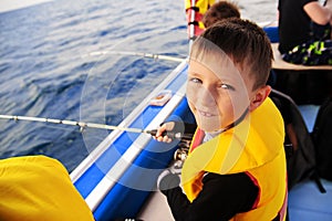 Little boy fishing with a spinning boat from a boat.