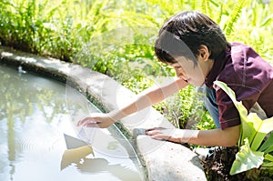 Little boy floating paper boat