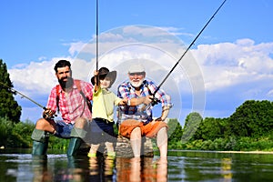 Little boy fly fishing on a lake with his father and grandfather. Summer day. Happy grandfather, father and grandson