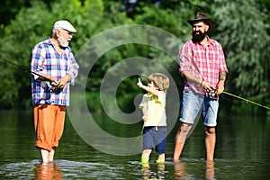 Little boy fly fishing in river with his father and grandfather.