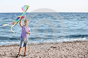 Little boy flying kite near sea